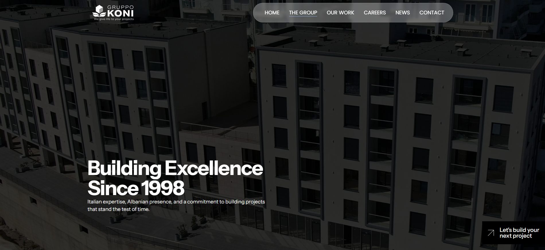Faqja «The Group»: titulli «Building Excellence Since 1998» mbi një fotografi të errësuar të një blloku banimi në ndërtim.